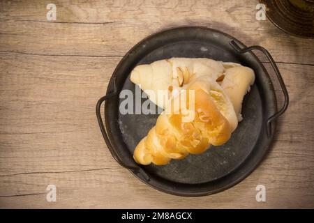 Elegantes französisches cremefarbenes Horngebäck in altem Tablett auf Holzbrett Stockfoto