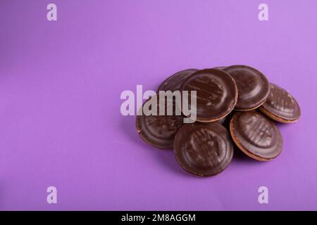 Runde Schokoladenkekse in Glasur auf farbigem Hintergrund Stockfoto