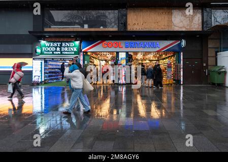 Cooles Britannia Souvenir Shop, Leicester Square, London, Großbritannien. Britischer Tourismus. Vorderseite anzeigen. Vorne lagern. Leute, die an einem nassen, regnerischen Winterabend vorbeigehen Stockfoto