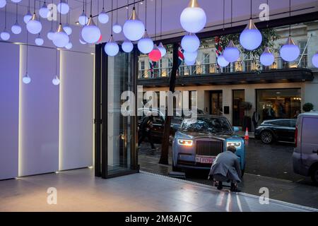 Ein Mitarbeiter von Rolls-Royce führt einen gebrauchten Rolls-Royce Phantom-Limousinenwagen der achten Generation am 12. Januar 2023 in London, England, in den Ausstellungsraum des Unternehmens, um ihn einem potenziellen Kunden auf der Berkley Street in Mayfair zu zeigen. Stockfoto