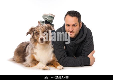 Mann mit seinem australischen Hirtenhund auf weißem Hintergrund Stockfoto