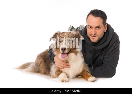 Mann mit seinem australischen Hirtenhund auf weißem Hintergrund Stockfoto