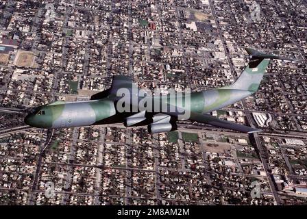 Eine Luft-zu-Luft-Ansicht von links eines C-141B Starlifter-Flugzeugs, das über einem Wohngebiet von San Bernardino fliegt. Staat: Kalifornien (CA) Land: Vereinigte Staaten von Amerika (USA) Stockfoto