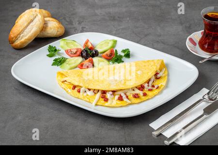 Omelett mit Fetakäse und türkischer Wurst auf einer weißen Porzellanplatte Stockfoto