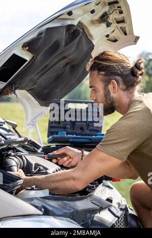 Mann, der im Motorraum eines Lieferwagens im Freien arbeitet Stockfoto