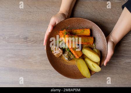 Draufsicht einer unbekannten Frau mit eingelegten Gurken, gebratenen Käsestiften und gebratenen Leberstücken. Stockfoto