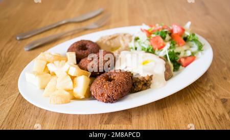 Falafel-Kombi-Gericht mit Gemüse. Faláfel oder falafel​ ist eine Kichererbse oder Bohnenkrokette. Es wird normalerweise im Nahen Osten konsumiert. Stockfoto