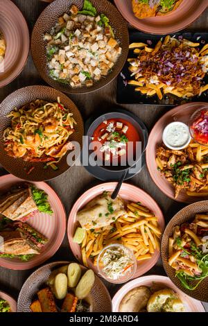 Blick von oben auf das Essen auf dem Tisch im Restaurant Cafe. Pasta mit Garnelen. Caesar Salat mit Croutons. Sandwiches mit Salat. Stockfoto