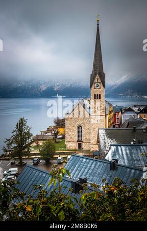 Hallstatt, Österreich - der weltberühmte Hallstatt, die zum UNESCO-Weltkulturerbe gehörende Stadt am See mit der Lutherischen Kirche Hallstatt an einem kalten nebligen Tag mit Schneefall Stockfoto