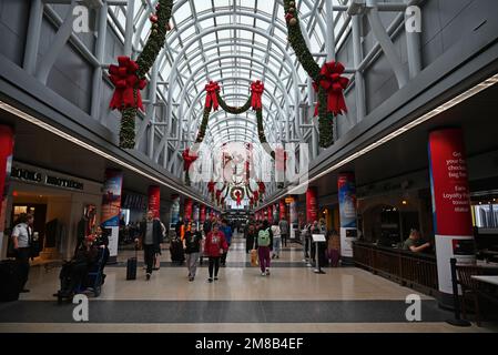 Reisende laufen unter den Oberlichtern und der Weihnachtsdekoration am Chicago O'Hare Airport in Terminal 3. Stockfoto