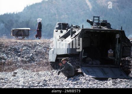 Ein südkoreanischer Marine besticht durch die offene Hintertür seines AAVP-7-Angriffsfahrzeugs, während eine Frau, die einen Wagen zieht, beim gemeinsamen US/Südkoreanisches Übungsteam Spirit '89 vorbeifährt. Subjekt Operation/Serie: TEAMGEIST '89 Land: Südkorea Stockfoto