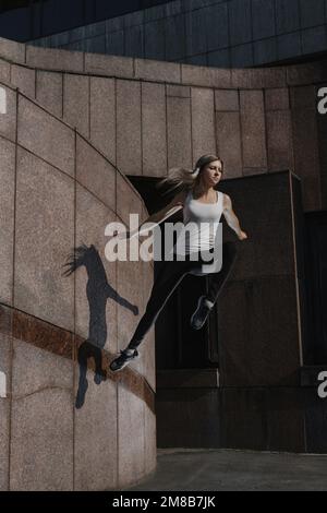 Junge Sportlerin, die Parkour in der Stadt macht. Das Mädchen ist in Freerunning verwickelt. Stockfoto