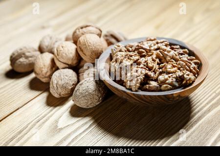 Geschälte Walnüsse und Nüsse in einer Schale in einer Holzschüssel aus Walnuss auf einem Holzhintergrund. Nüsse und gesundes Essen Konzept Stockfoto