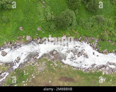 Fluss, Draufsicht. Der Wasserstrom fließt durch Stone Boulders River in einem grünen Tal. Wildes Bergwasser am Sommertag Stockfoto