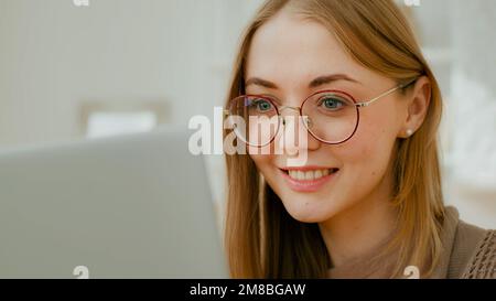 Nahaufnahme Weiße Frau weibliches Gesicht Mädchen mit Brille Augen auf Laptop Bildschirm. Freiberufler lächelnde Geschäftsfrau, die mit Computerarbeit beschäftigt ist und schlecht lernt Stockfoto