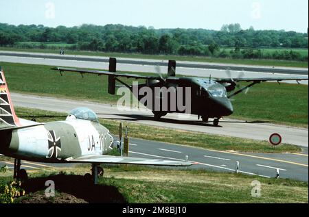 Ein C-23 Sherpa Aircraft Taxi auf der Landebahn in der Nähe des F-86 Sabre Aircraft des deutschen fliegenden Ass Erich Hardtmann. Basis: Luftwaffenstützpunkt Wittmundhaven Land: Bundesrepublik Deutschland (BRD) Stockfoto