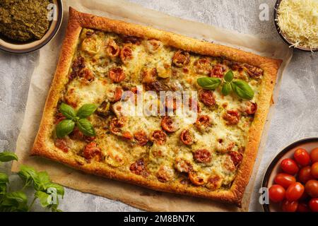 Hausgemachter Blätterkuchen mit Pesto, Tomaten und Mozzarella wie Pizza Caprese. Stockfoto