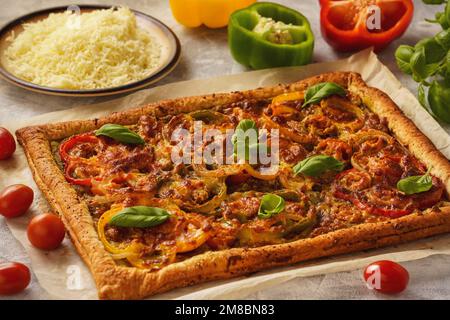 Hausgemachter Blätterkuchen mit Pesto, Tomaten, Paprika und Mozzarella. Stockfoto