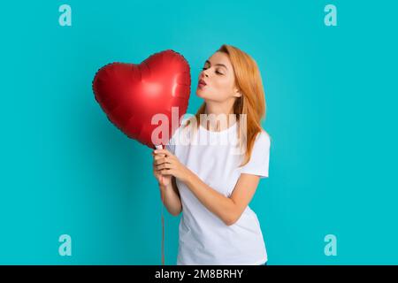 Frau in der Liebe, Luftkuss. Ein junges Mädchen mit roten Luftballons. Valentinstag. Isoliert auf blauem Hintergrund. Stockfoto