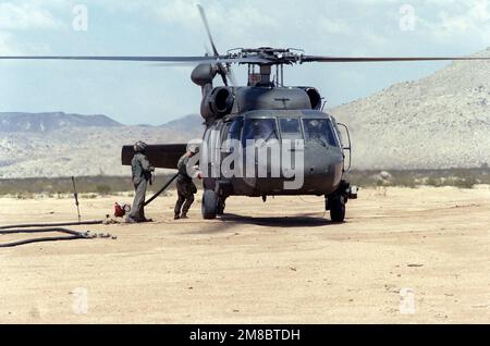 Soldaten des 24. Luftfahrtbataillons betanken einen im Leerlauf fahrenden UH-60 Black Hawk Helikopter während der Rotation der Einheit zum National Training Center. Basis: Fort Irwin Bundesstaat: Kalifornien (CA) Land: Vereinigte Staaten von Amerika (USA) Stockfoto