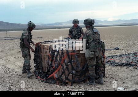 Drei Mitglieder des 24. Stützbataillons bereiten eine Palette von Rationen für die Hubschrauberabholung am Bicycle Lake während der Rotation der Einheit zum National Training Center vor. Basis: Fort Irwin Bundesstaat: Kalifornien (CA) Land: Vereinigte Staaten von Amerika (USA) Stockfoto