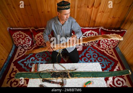 (230113) -- ALTAY, 13. Januar 2023 (Xinhua) -- Ein Hirte zeigt ein Paar fellbedeckte Skier zu Hause in der Präfektur Altay, Nordwestchina, Uygur Autonomous Region Xinjiang, 22. Dezember 2022. Die Präfektur Altay ist bekannt für ihre lange Wintersaison, die bis zu acht Monate pro Jahr dauern kann. Mit seinem weitläufigen natürlichen Pulverschnee zieht es Skifahrer weltweit an. Die Region hat sich in den letzten Jahren bemüht, den Wintertourismus anzukurbeln und Besucher mit Skifahren, Eisangeln und anderen Winteraktivitäten zu verführen. Zwischen dem 2022. Dezember und dem 11. Januar 2023 wurden rund 1,02 Millionen Touristen aufgenommen. (Xinhua/Hu Huhu) Stockfoto