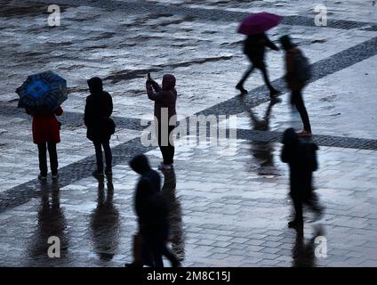 Hamburg, Deutschland. 13. Januar 2023. Passanten gehen bei Regen und Sturm durch den Rathausplatz im Stadtzentrum. Kredit: Christian Charisius/dpa/Alamy Live News Stockfoto