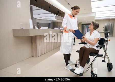 Therapeut kommuniziert mit einer älteren Frau im Rollstuhl Stockfoto