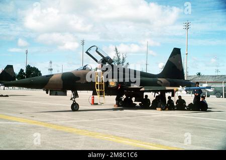 Thailändische Bodenteams sitzen im Schatten unter einem Royal Thai Air Force F-5E Tiger II Flugzeug während der gemeinsamen Thai/US-Übung Thalay Thai '89. Betreff Operation/Serie: THALAY THAI '89 Stützpunkt: Utapao Luftwaffenstützpunkt Land: Thailand (THA) Stockfoto