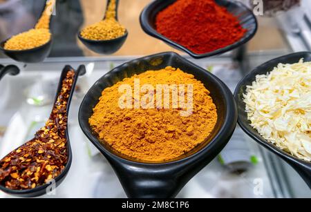 Kurkumpulver Gewürz in schwarzer Schüssel und andere Gewürze auf dem Markt. Selektiver Fokus. Stockfoto