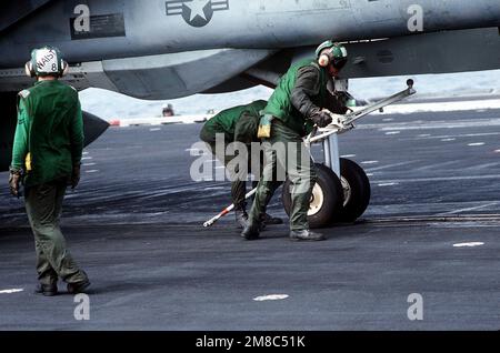 Katapultbesatzungsmitglieder positionieren ein F-14 Tomcat-Flugzeug auf einem Katapult auf dem Cockpit des Flugzeugträgers USS Constellation (CV-64) während des PACEX 89. Betreff Operation/Serie: PACEX '89 Land: Unbekannt Stockfoto