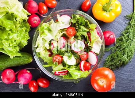 Frischer Salat mit Gurken, Tomaten, Radieschen und Kräutern. Draufsicht Stockfoto