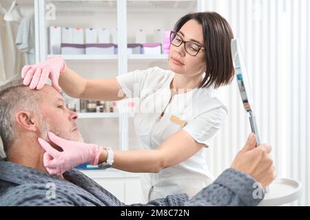 Brillenkosmetikerin konsultiert einen älteren Mann Stockfoto