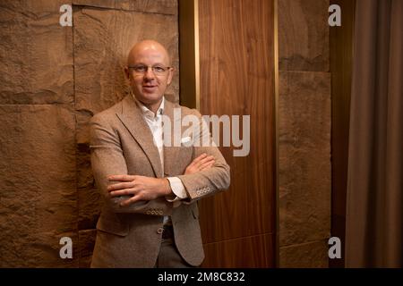 Kahlköpfiger, wohlwollender Mann mittleren Alters steht an der Wand Stockfoto