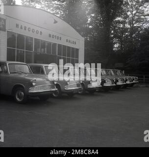 1959, historisch, Reihe neuer Ford Angiia 105E Autos vor der Garage, Hargood Motor Sales, Wilmslow Rd, East Didsbury, Parrs Wood, Manchester, England, Großbritannien. Die Anglia 105E mit ihrem neuen amerikanischen Stil war das vierte von Ford veröffentlichte Anglia-Modell und wurde von 1959 bis 1968 mit über einer Million gefertigten Maschinen produziert. Stockfoto