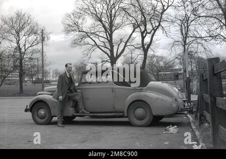 1950er, historisch, ein Mann, der neben seinem leicht zerschmetterten Auto stand, parkte in der Hargood Garage an der Wilmslow Rd in Didsbury, Manchester, England. Stockfoto