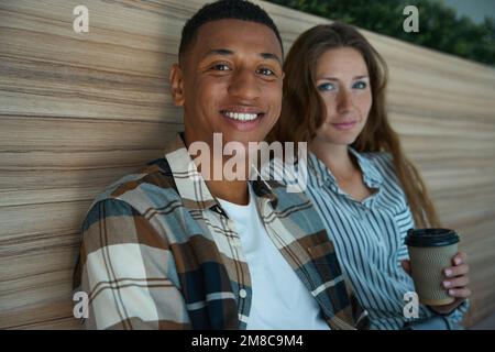 Ein glücklicher Mann, der neben seiner Kollegin sitzt Stockfoto