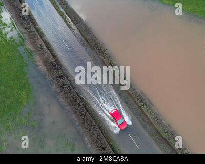 Sutton St Nicholas, Herefordshire, Großbritannien – Freitag, 13. Januar 2023 – UK Weather – Luftaufnahme eines Fahrzeugs, das vom nahe gelegenen Fluss Lugg auf einer Landstraße zwischen Sutton St Nicholas und Hereford durch Überschwemmungen fährt. Nach Tagen der Regenfälle befinden sich die örtlichen Flüsse wie der Fluss Lugg, der Fluss Teme und der Fluss Wye auf sehr hohem Niveau. Mehr Regenvorhersage. Foto Steven May/Alamy Live News Stockfoto