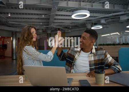 Glücklicher Mann und glückliche Frau, die im Lobbybüro zusammen jubeln Stockfoto