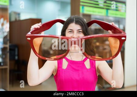 Eine weiße Frau mit einer riesigen roten dekorativen Brille. Stockfoto
