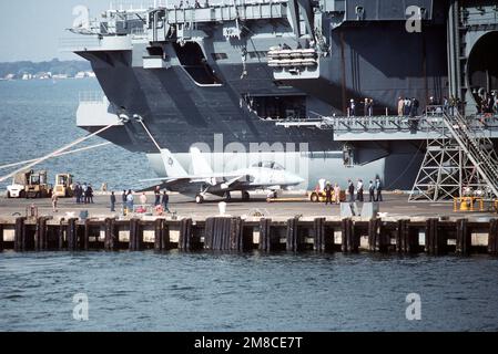 Ein MD-3A Schlepper zieht ein Fighter Squadron 41 (VF-41) F-14A Tomcat Flugzeug entlang Pier 12, um das Flugzeug an Bord des nuklearbetriebenen Flugzeugträgers ABRAHAM LINCOLN (CVN-72), Hintergrund, zu laden. Das Flugzeug wird am 11. November bei der Inbetriebnahmezeremonie des Schiffes an einer Cockpit-Ausstellung teilnehmen. Basis: Marine Air Station, Norfolk Bundesstaat: Virginia (VA) Land: Vereinigte Staaten von Amerika (USA) Stockfoto