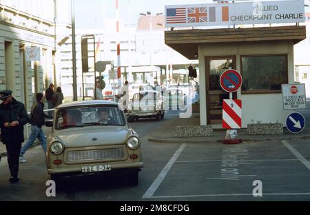 Ostdeutscher fahren mit ihrem Auto durch Checkpoint Charlie und nutzen die lockeren Reisebeschränkungen für einen Besuch in Westdeutschland. Basis: Berlin Land: Deutschland / Deutschland (DEU) Stockfoto