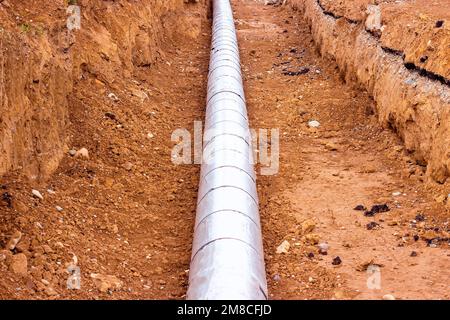 Installation der Verteilungseinheit des Heiz- und Wasserversorgungsnetzes. Rahmen für die Verbindung von Rohren im Erdgraben. Stockfoto