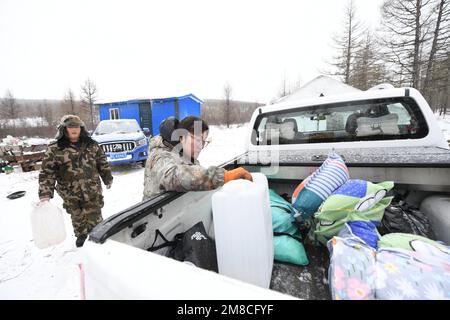 (230113) -- GENHE, 13. Januar 2023 (Xinhua) -- Juele und seine Cousine Dalinma bereiten sich darauf vor, Wasser in einer temporären Herdstation am Jinhe Forest Range in der Nähe von Genhe City, Nordchina Autonome innere Mongolei, zu holen, 12. Januar 2023. Alle zwei oder drei Tage fährt Juele Bulituotian zum Jinhe-Waldgebiet etwa 80 Kilometer von Genhe City entfernt. Dort wird der 39-jährige Aoluguya Ewenki-Hirte, der einen traditionellen Pelzmantel trägt, sein forschendes Rentier finden. Anstatt Rentiere in einer Scheune zu halten, ließen die Ewenki-Hirten die Tiere im Wald leben und überprüften sie alle paar Tage Stockfoto