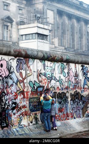 Westdeutsche Kinder versuchen, ein Stück der Berliner Mauer als Souvenir abzuschlagen. Ein Teil der Mauer wurde bereits am Potsdamer Platz abgerissen. Basis: Land Berlin: Deutschland (DEU) Stockfoto