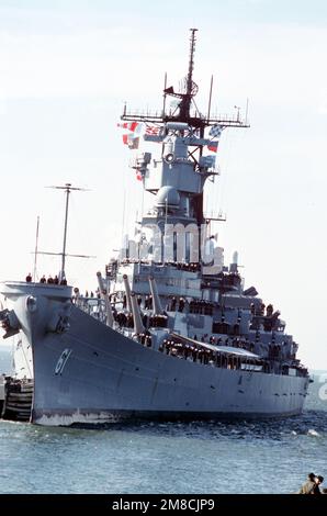 Ein Hafenbogenblick auf das Schlachtschiff USS IOWA (BB 61), während das Schiff mit einem großen Schlepper zum Pier manövriert wird. Die IOWA kehrt nach dem Einsatz zum Heimathafen zurück. Basis: Marine Air Station, Norfolk Bundesstaat: Virginia (VA) Land: Vereinigte Staaten von Amerika (USA) Stockfoto