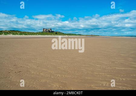 4. Juli 2022 - Bamburgh, Großbritannien: Das historische Bamburgh Castle am Horizont über Bamburgh Beach, Northumberland, Großbritannien, liegt in nordwestlicher Richtung Stockfoto