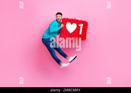 Ganzkörperfoto von einem jungen netten Kerl springt Influencer Herzbenachrichtigung gekleidet stilvolle blaue Kleidung isoliert auf pinkfarbenem Hintergrund Stockfoto