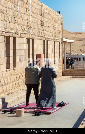 LUXOR, ÄGYPTEN - 27. Dez. 2022. Vertikale Ansicht zweier arabischer muslimischer Männer, die mitten in der Zeit auf einem traditionellen Teppich beten Stockfoto