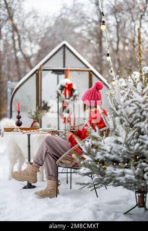 Eine Frau im verschneiten Hinterhof in den Winterferien Stockfoto